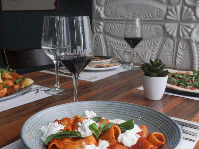Plato de pasta y copa de vino servido en una franquicia de la mafia