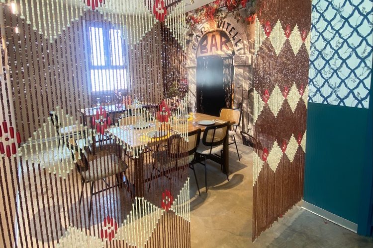 Mesa del comedor tras una cortina de cuentas, junto a la pared de azulejos