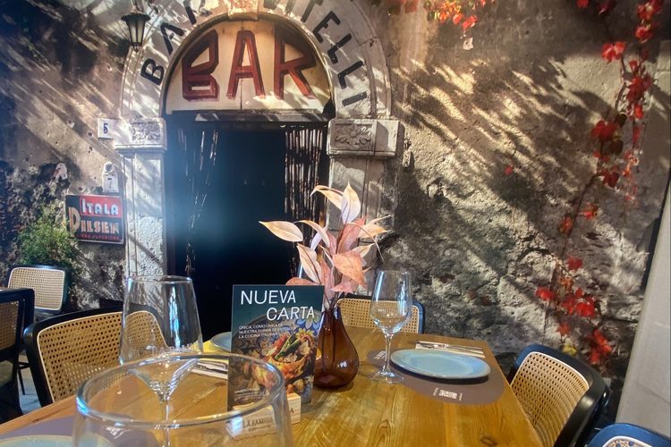 Mesa junto al mural del Bar Vitelli, con la carta de temporada sobre el tablero