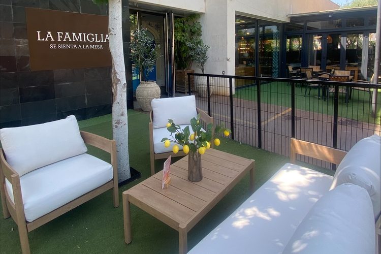 Terraza exterior con sofás blancos y limoneros a la entrada de La Famiglia Playa de San Juan