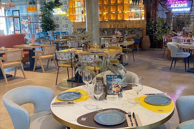 Sala principal con mesas redondas, sillas tapizadas y columnas de hormigón