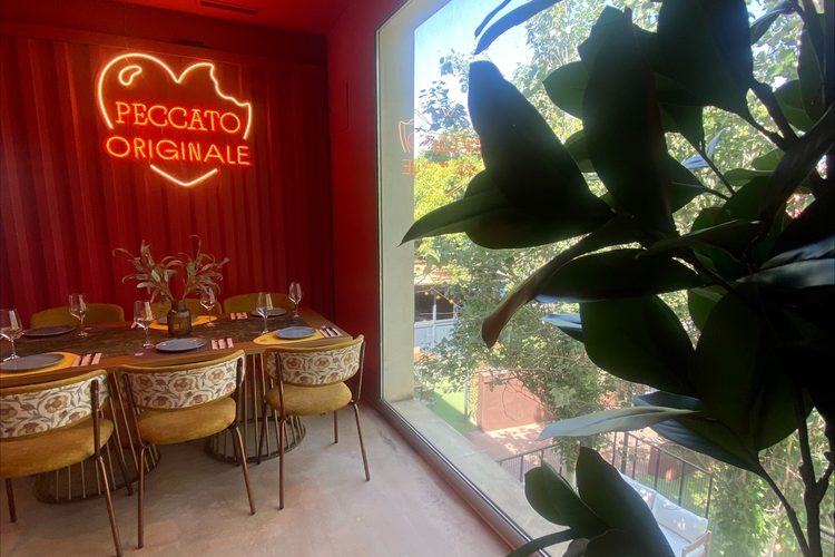 Reservado de pared roja con el rótulo de neón Peccato Originale
