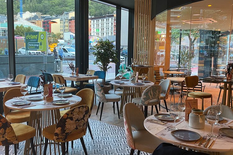 Sala acristalada con mesas preparadas para comer y vistas a la avenida de Escaldes-Engordany, Andorra