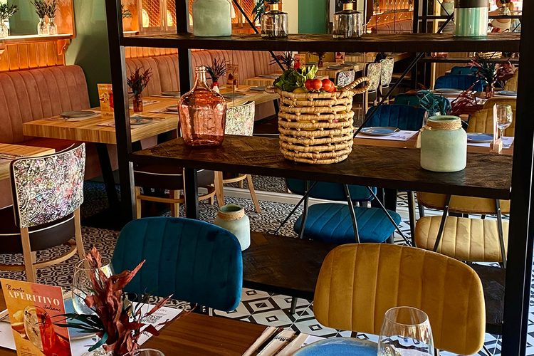 Cesta de verduras frescas y sillas de terciopelo en el interior del restaurante italiano de Andorra