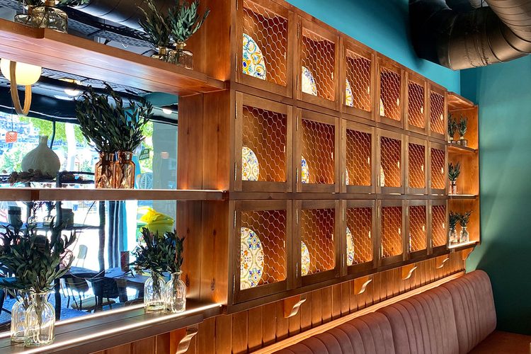 Pared de madera con hornacinas de azulejos y ramas de olivo en la decoracion del restaurante italiano en Andorra