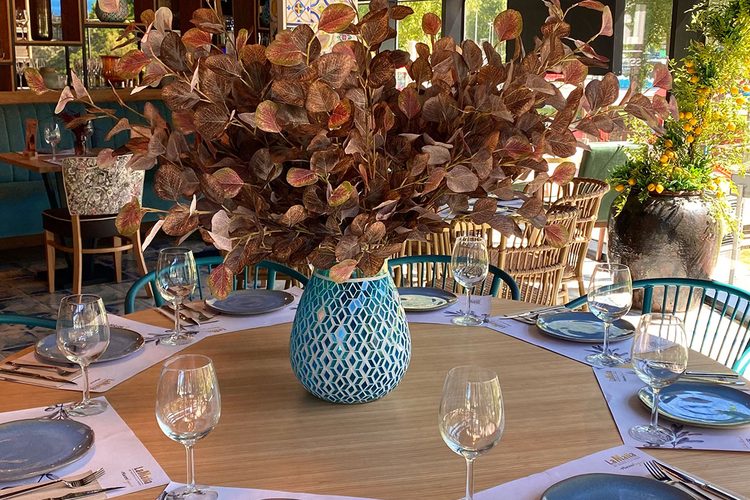 Mesa redonda con vajilla azul y centro floral lista para una comida en grupo en el italiano de Andorra